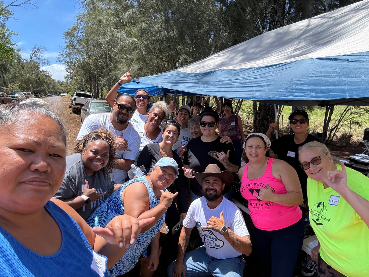 Holomua Outreach volunteers gathered beneath a shade tent after a community cleanup